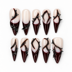 Gothic thorn press-on nails in nude and deep burgundy with glossy tips and sculptural black spike details