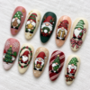 Diagonal view of Christmas press-on nails with gnomes, Christmas trees, snowflakes, bows, and bells on white linen