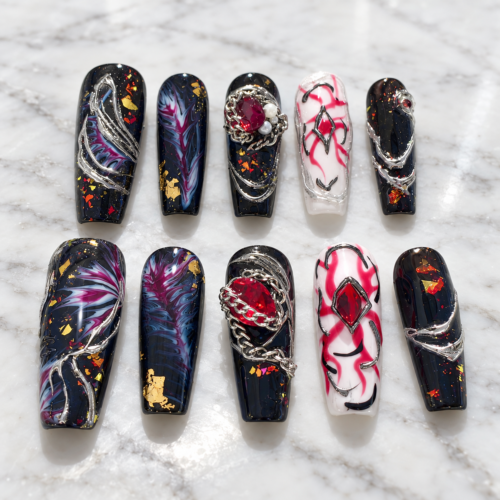 midnight nebula press-on nails with starry black tips, blue-magenta swirls, gold flecks, silver chains and red gems
