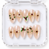 Holiday pearl press-on nails in blush pink with gold bows, red gem centers, holly berries and wreath-like jewel details.