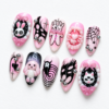 Pink and black press-on nails featuring rabbit and spiderweb patterns.