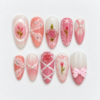 Pink rose press-on nails with blush tones, white lace patterns, sculpted roses, bows and pearl-like accents