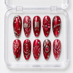 Ruby red fan press-on nails with glitter, silver ornamental lines, stars, a flower, bow and shell-inspired details.