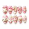 Press-on nails with 3D bunny and puppy faces, strawberries, dessert details, a pink bow, and pearl-like beads.