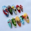 Press-on nails featuring a green apple design and whimsical musical notes.